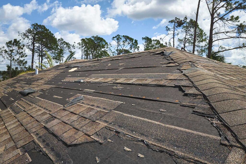 A roof with missing and damaged shingles after a storm.