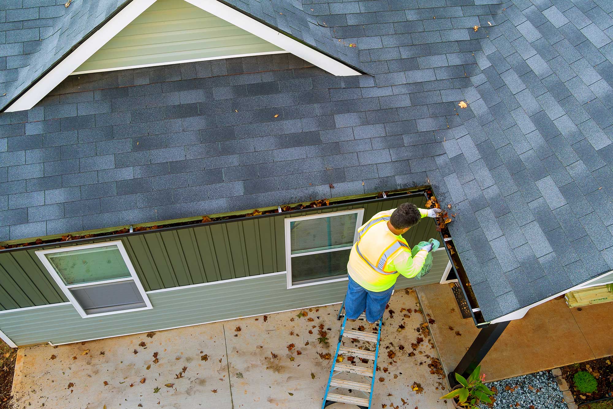 Technician clearing debris from a residential gutter to prevent water damage
